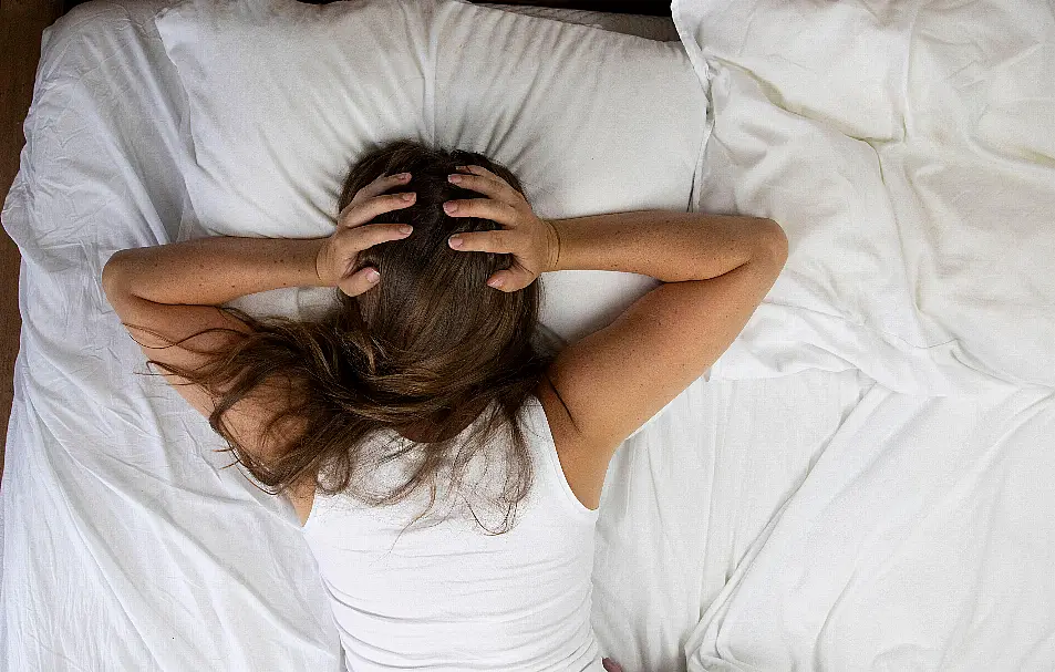 Woman lying in bed not being able to sleep in the heat