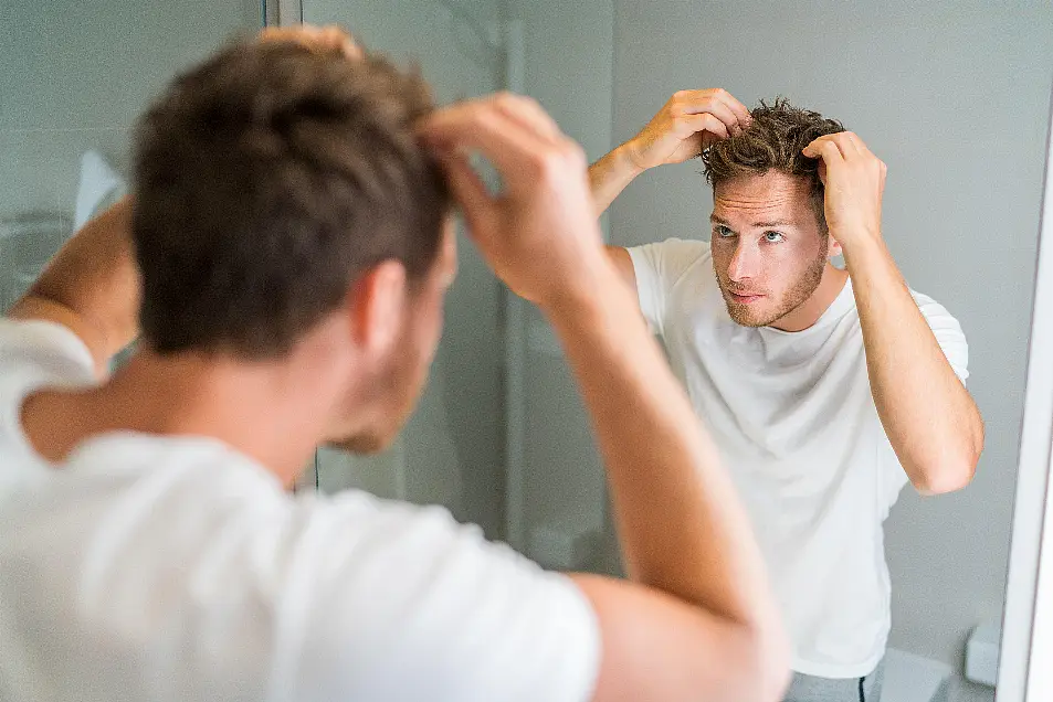 man looking at scalp in mirror