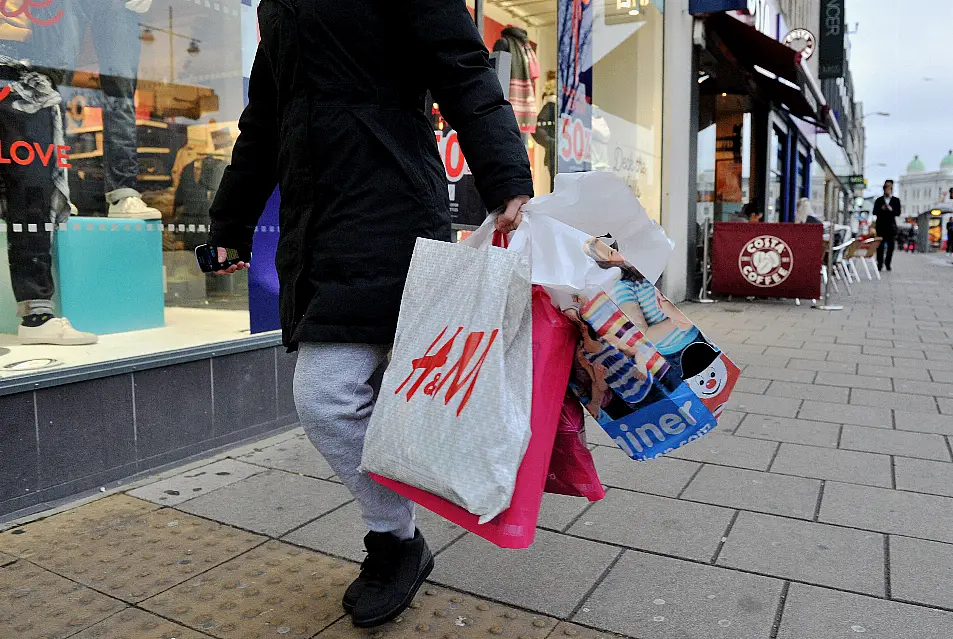 woman walking along street carrying shopping bags