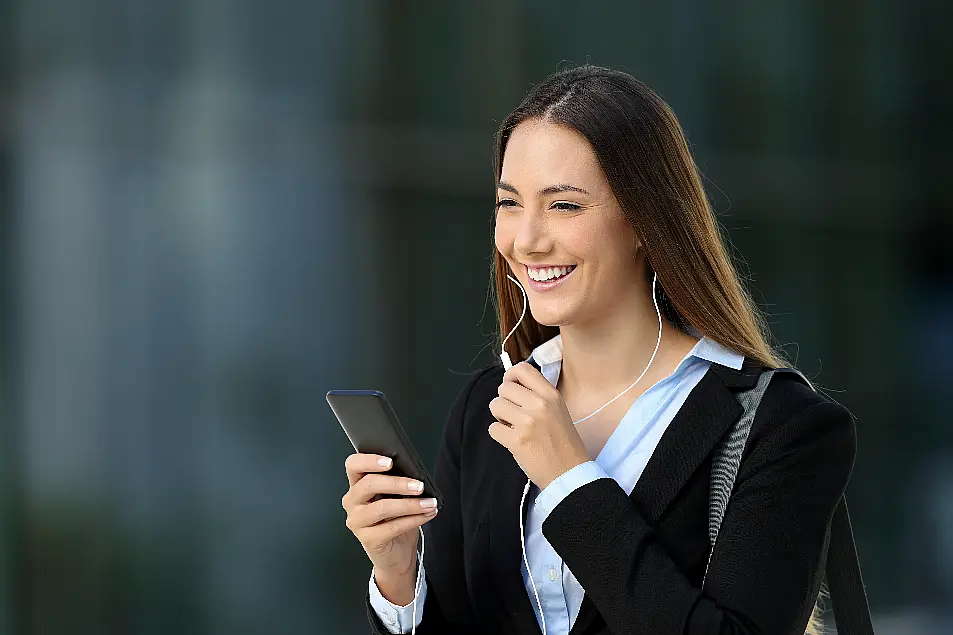 Happy executive talking with earphones during a phone call on the street