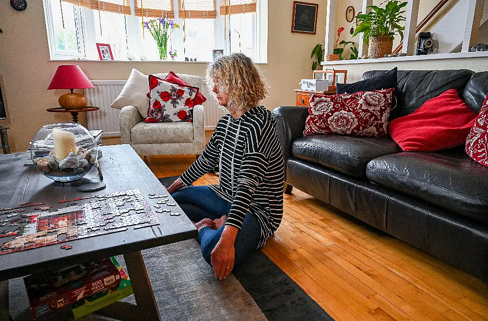 A mature middle aged woman doing relaxation mindfulness and breathing exercises at home watching a lesson on her smartphone