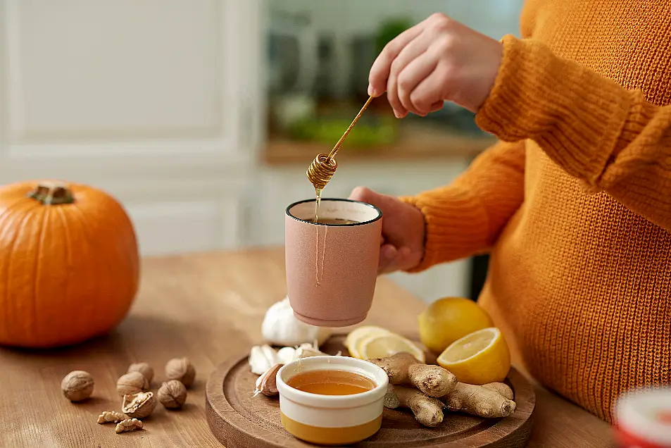 A woman mixing honey and lemon into hot water