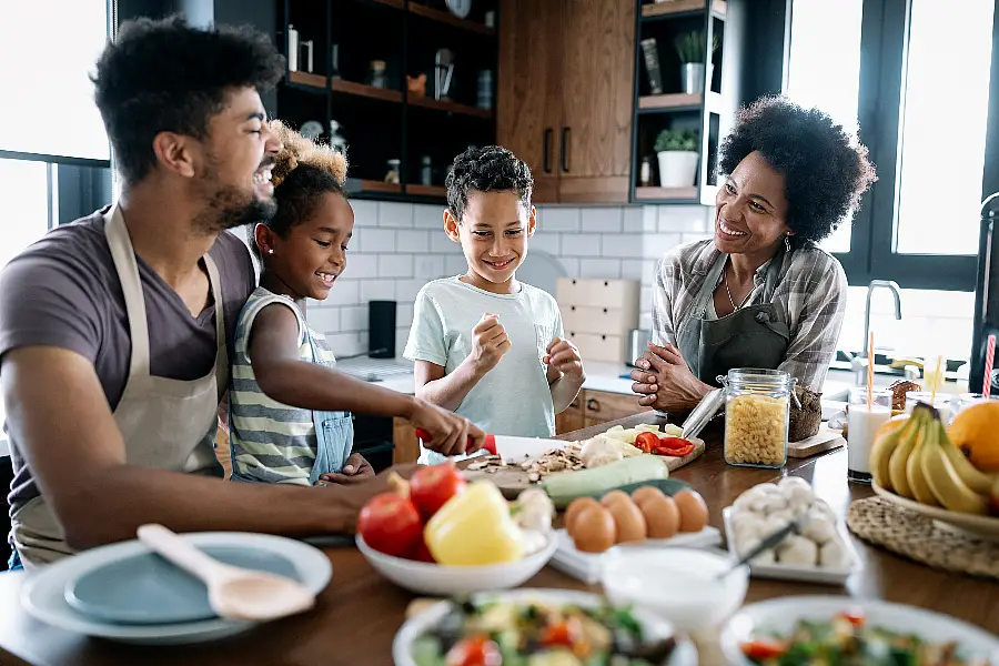 Healthy food at home. Happy black family in the kitchen having fun and cooking together