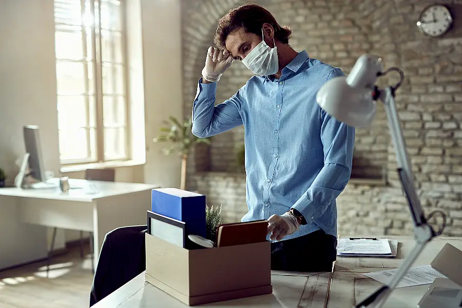 Young sad businessman packing his belongings after being fired during COVID-19 pandemic.