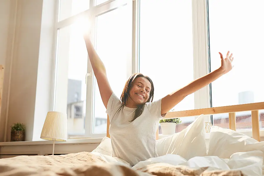 Woman just woken up in bed looking happy and well rested