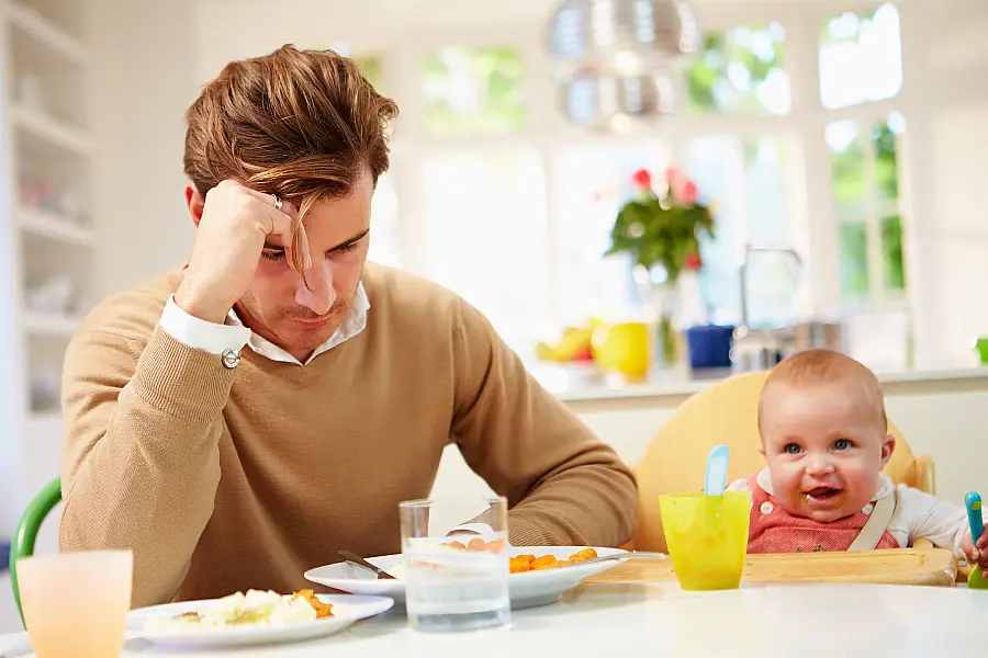 Father looking sad next to baby