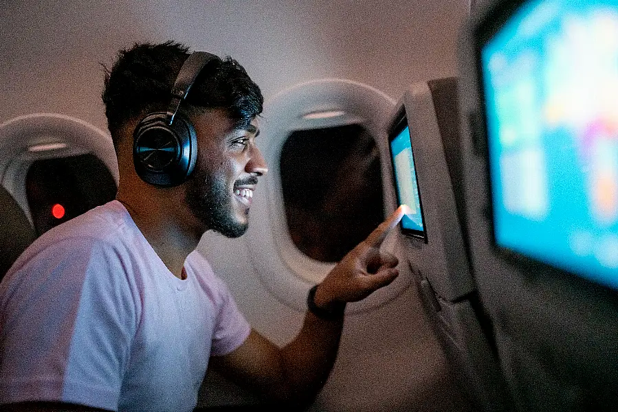 Passenger in airplane touching LCD entertainment screen