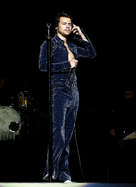 Harry Styles performing in a blue glittery jumpsuit in 2019 