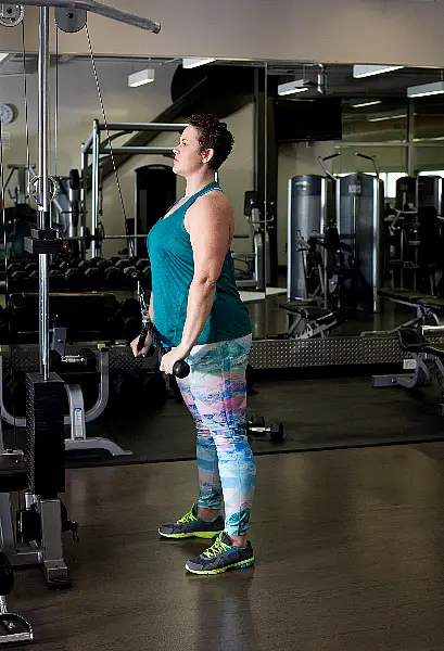 Woman using weights machine in gym