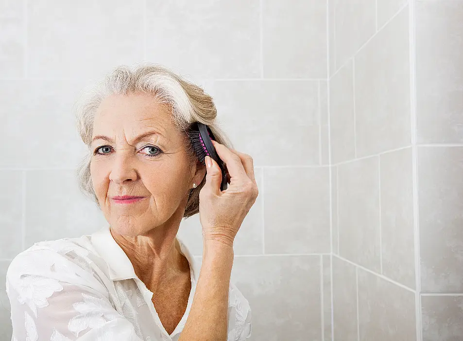 woman brushing her hair in front of the mirror