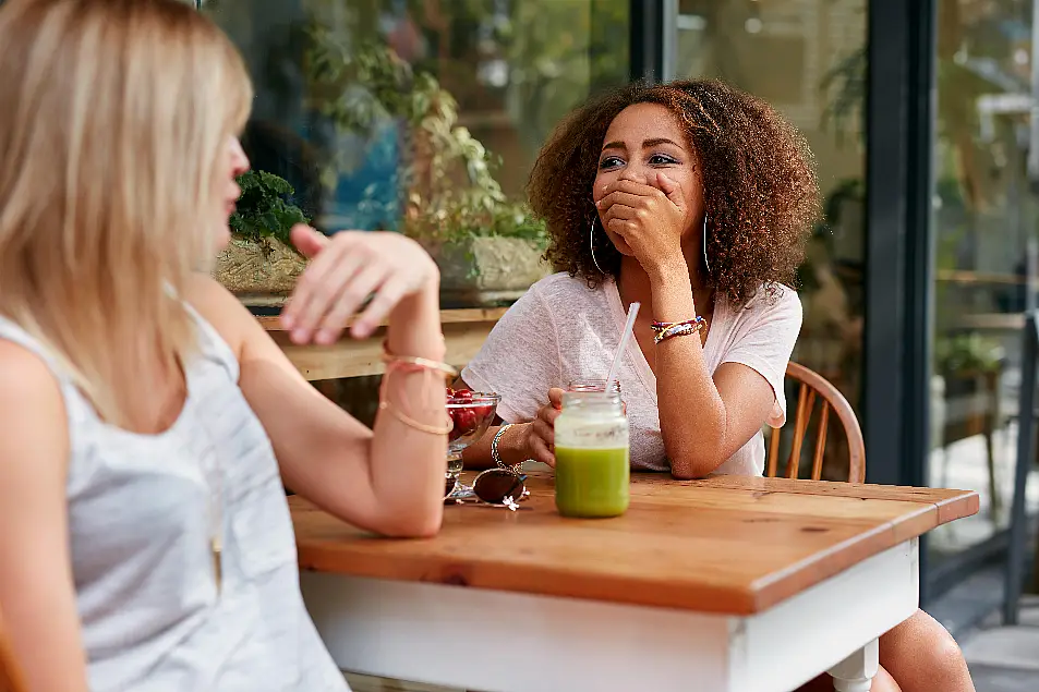 Two female friends out for a drink together, laughing and chatting