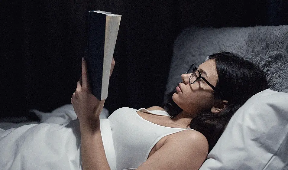 woman reading book in bed