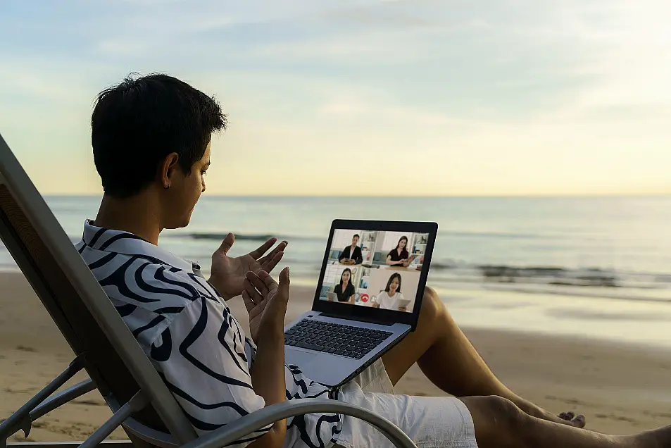 Man working online from a tropical beach with laptop