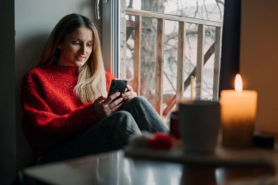 Woman sat with a phone in hand (Alamy/PA)