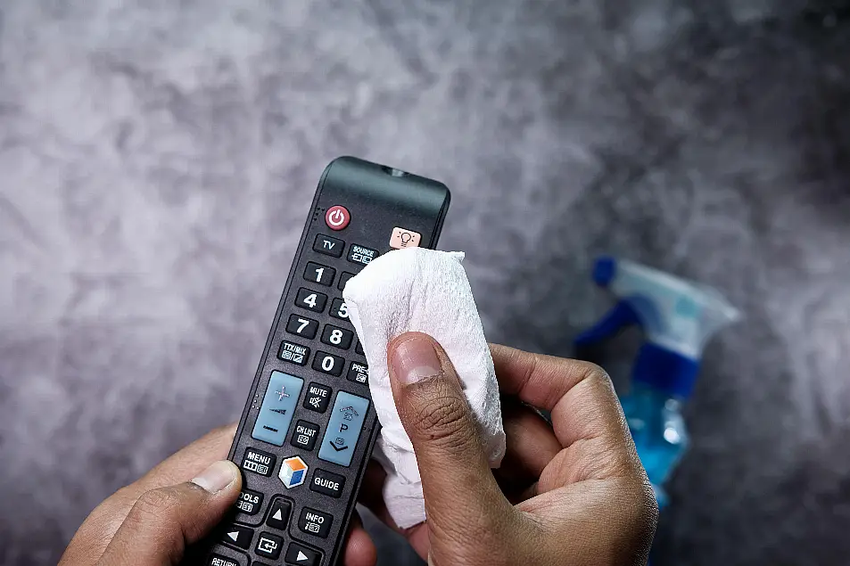 Man disinfecting TV remote control