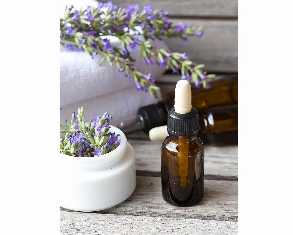 Dropper bottle with lavender essential oil and fresh towels in background