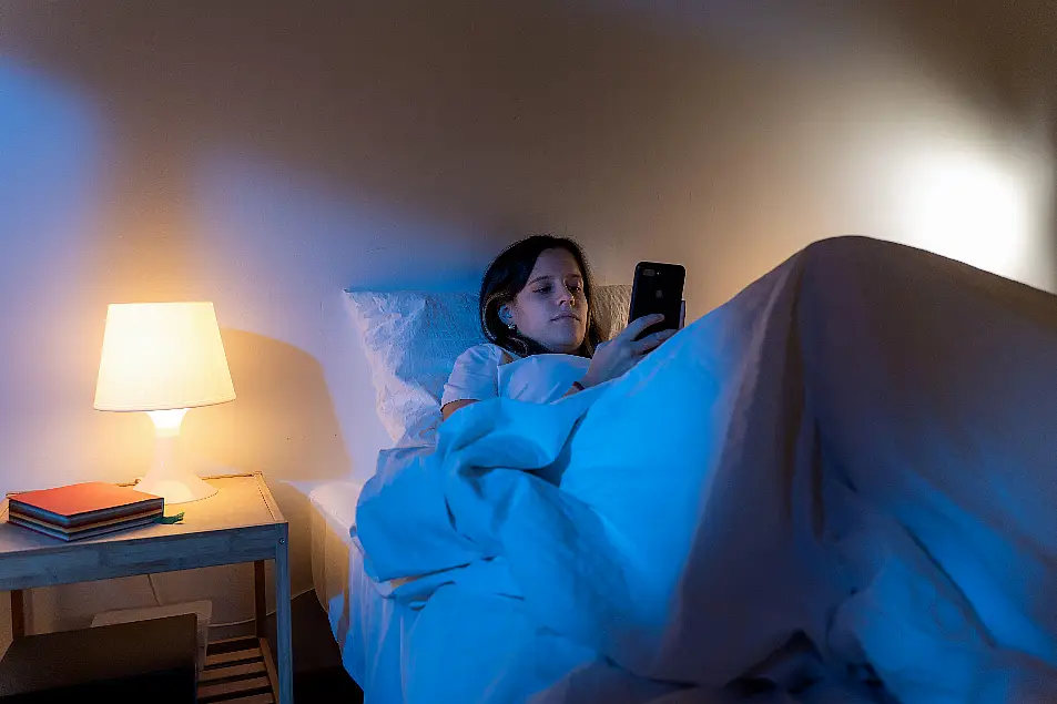 Girl looking her smart phone doom scrolling on bed in the middle of the night