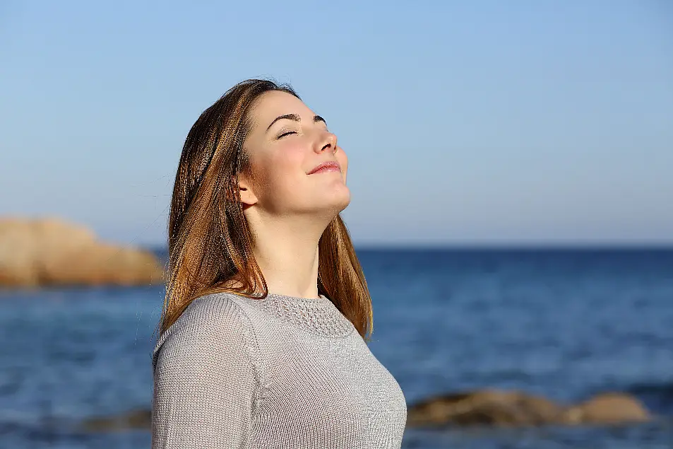 Happy relaxed woman breathing deep fresh air on the beach 