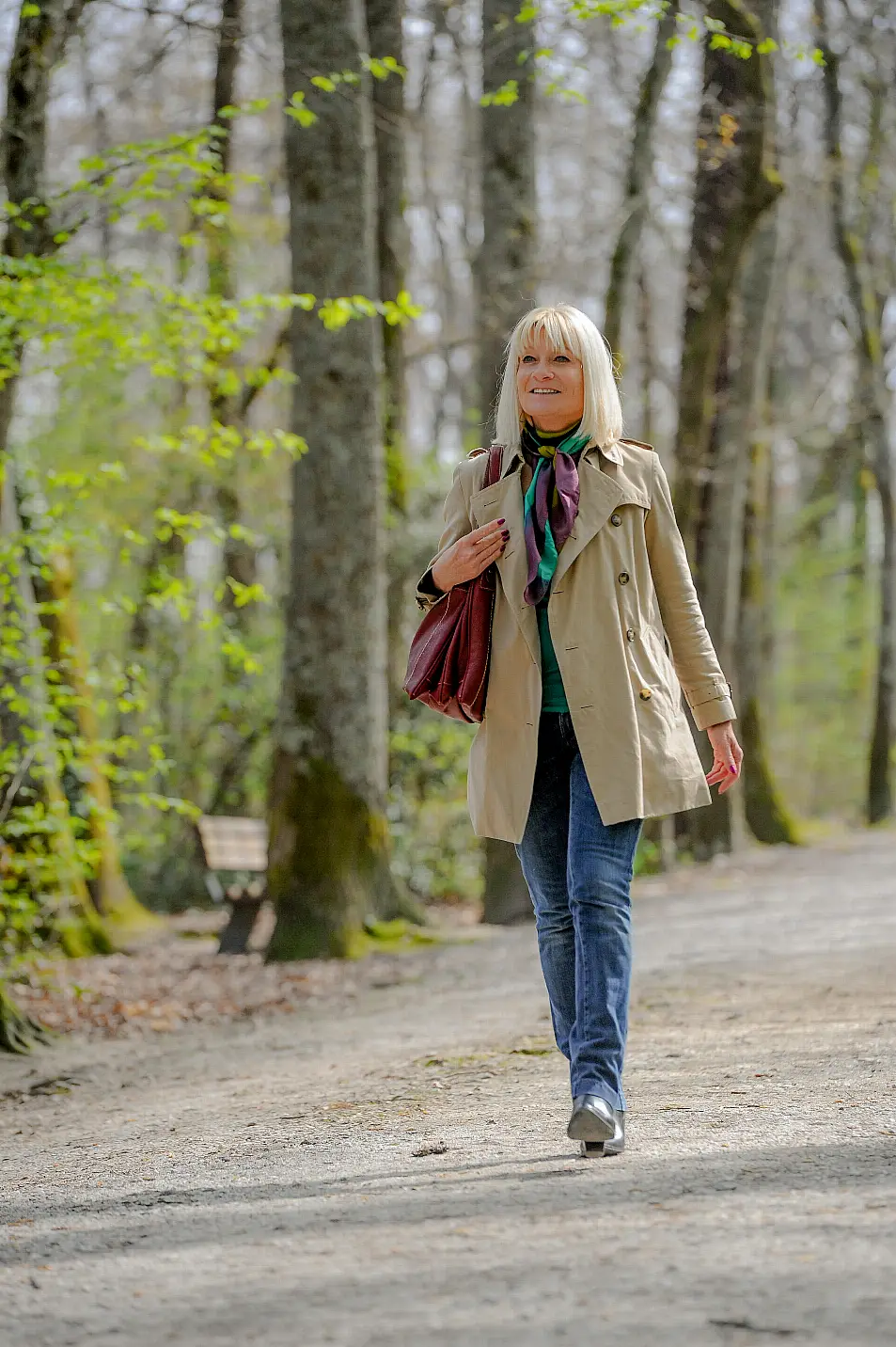 Senior woman walking through a park while smiling 