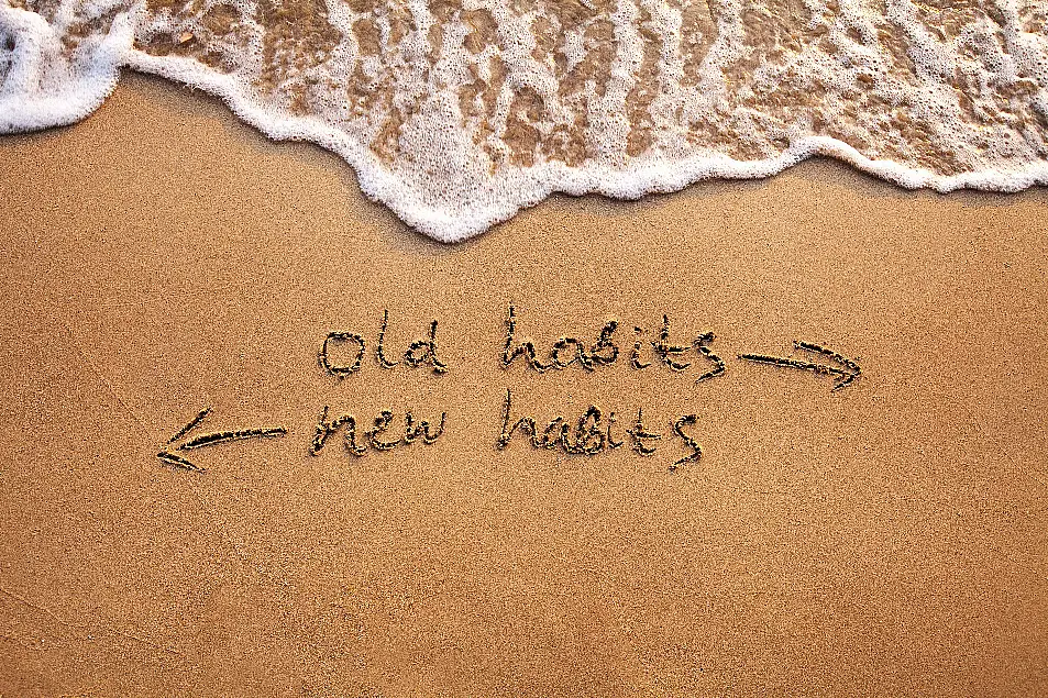 Old habits vs new habits written in the sand 