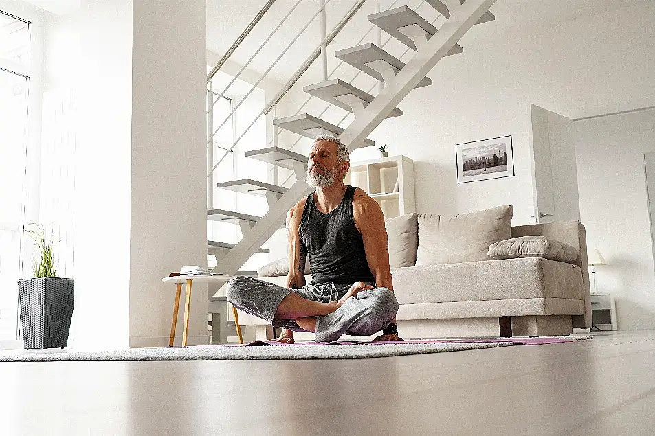 Senior man doing yoga on a mat at home