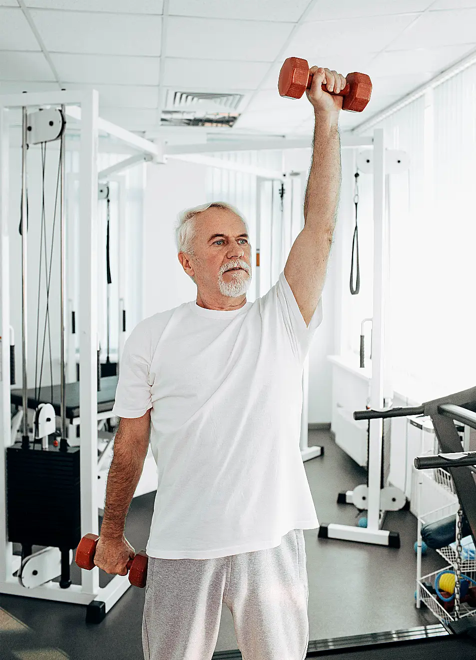 Senior man lifting weights at an exercise class 