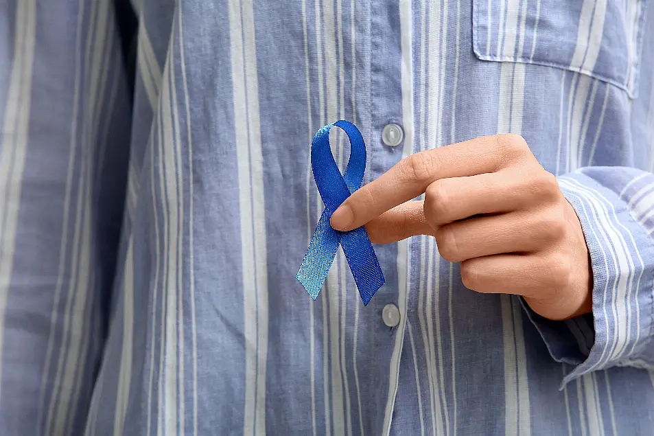 Cropped image of woman wearing blue striped shirt holding a blue ribbon for colorectal cancer