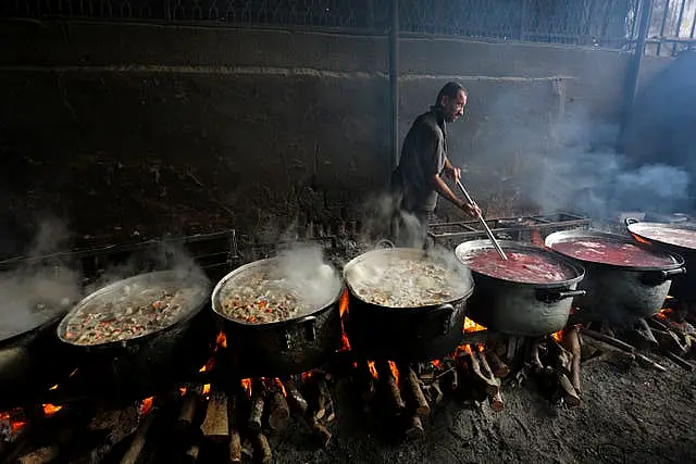 A Palestinian cooks food for people displaced in the ongoing Israeli bombardment of the Gaza Strip