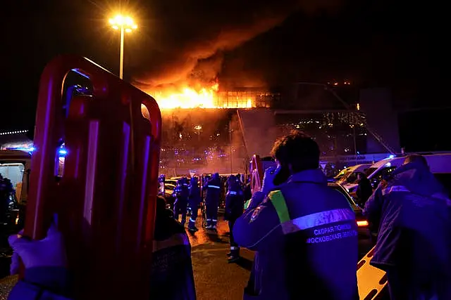 A medic stands near ambulances parked outside the burning building of Crocus City Hall on the western edge of Moscow, Russia 