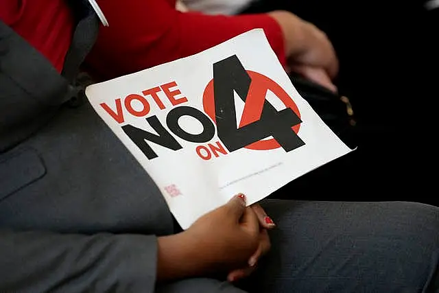 A person in the audience holds a sign against Amendment 4 