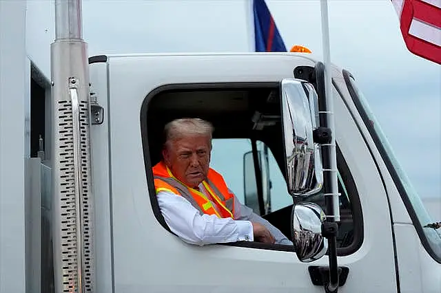 Donald Trump talks to reporters as he sits in a garbage truck