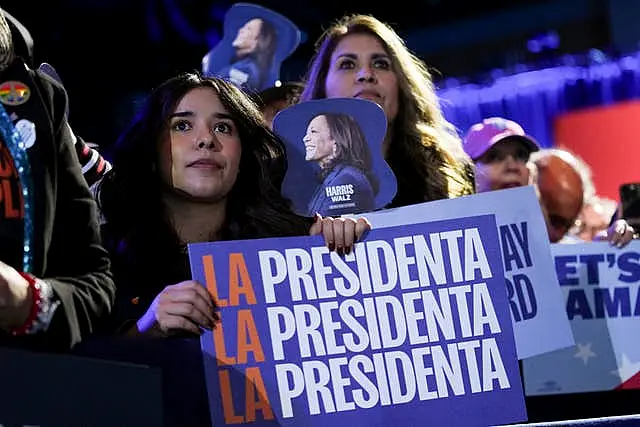 Women hold a Kamala Harris poster