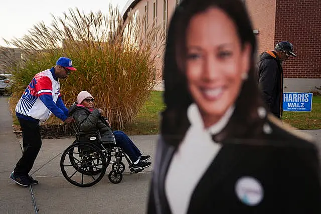 Liza Fortt, 74, centre, accompanied by her son Timothy Walker, left, and husband Willie Fortt, moves in line to cast her ballot for Democratic presidential nominee vice president Kamala Harris at her polling place at Scranton High School in Scranton, Pennsylvania