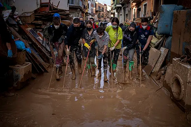 Volunteers and residents clean the mud from the streets in an area affected by floods in Paiporta, Valencia, Spain