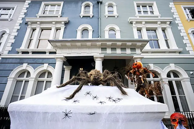 A giant spider sitting on a coffin in front of a house decorated for Halloween on Elgin Crescent in Notting Hill, west London